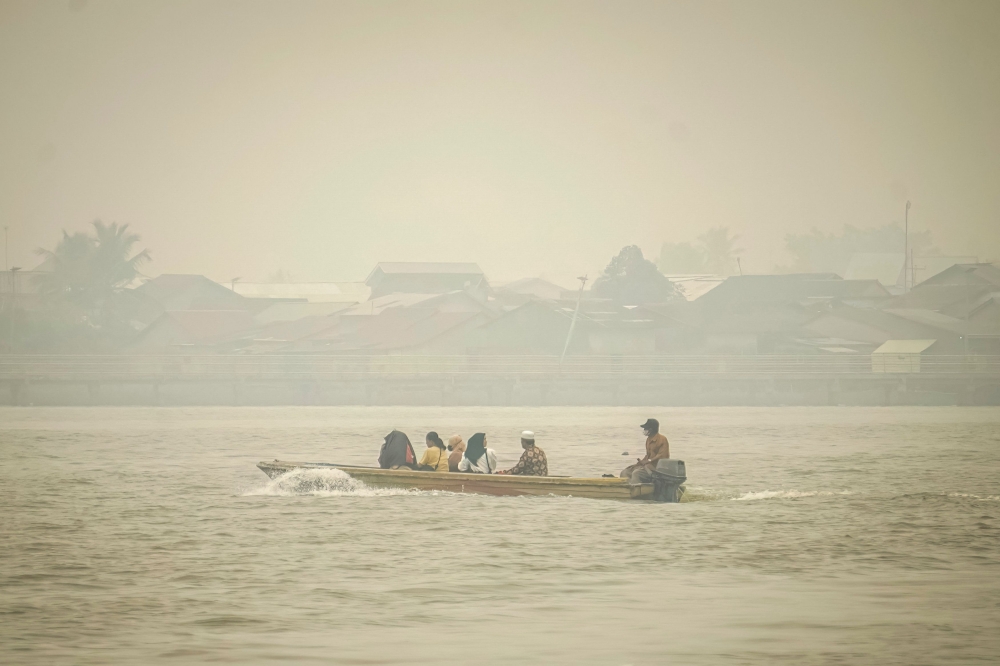 People travel on a river boat as thick haze from forest and land fires blankets Benua Melayu Darat village in Pontianak, West Kalimantan, on September 16, 2026. (Photo by DITO / AFP)