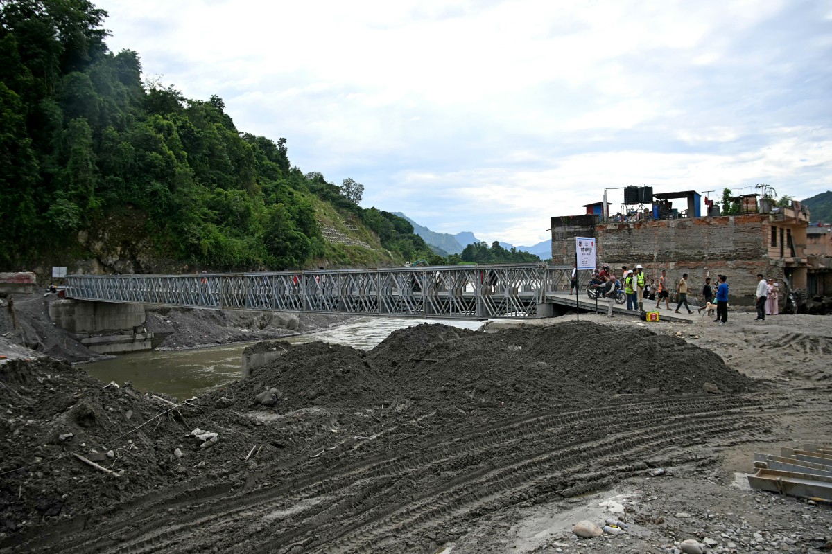 People commute across a bridge over the Tadi river, rebuilt by army personnel in the aftermath of flash floods at Devighat in Nepal's Nuwakot district on September 11, 2026. (Photo by PRAKASH MATHEMA / AFP)
