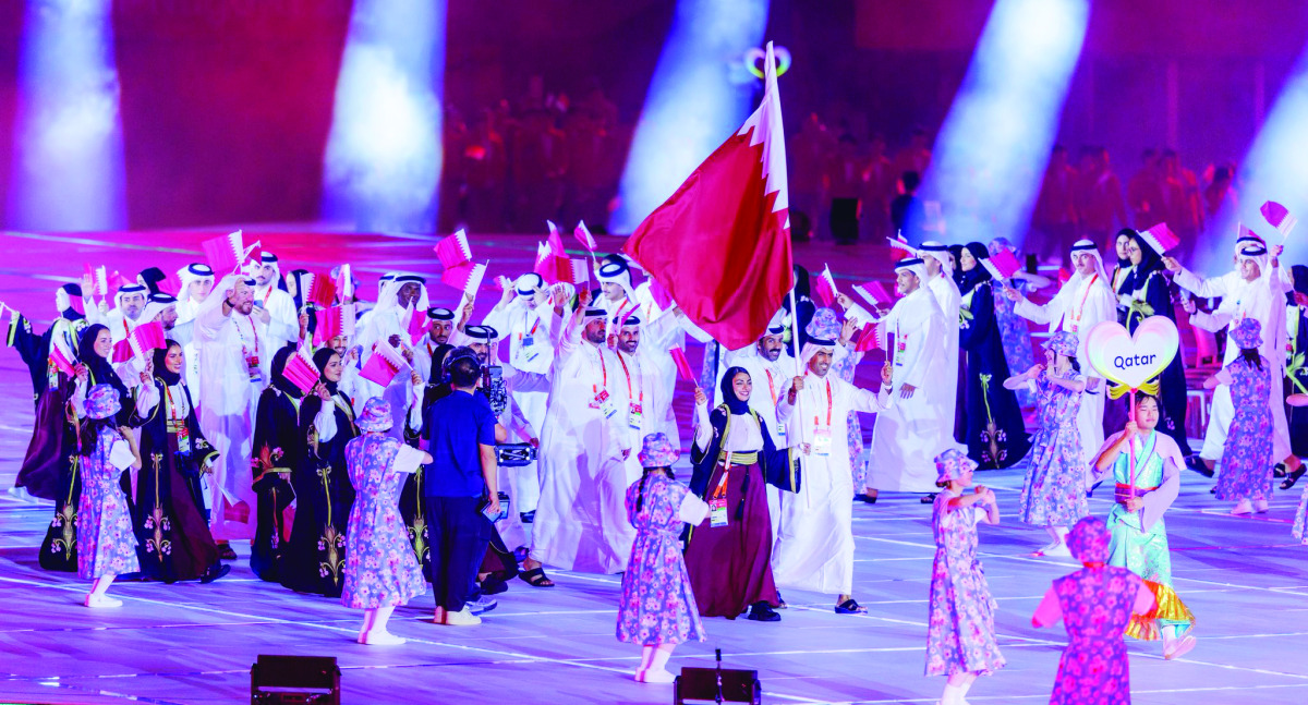 Mohammed Saadon Al Kuwari and Reem Al Sharshani carry the national flag as Qatari athletes march during the opening ceremony.



