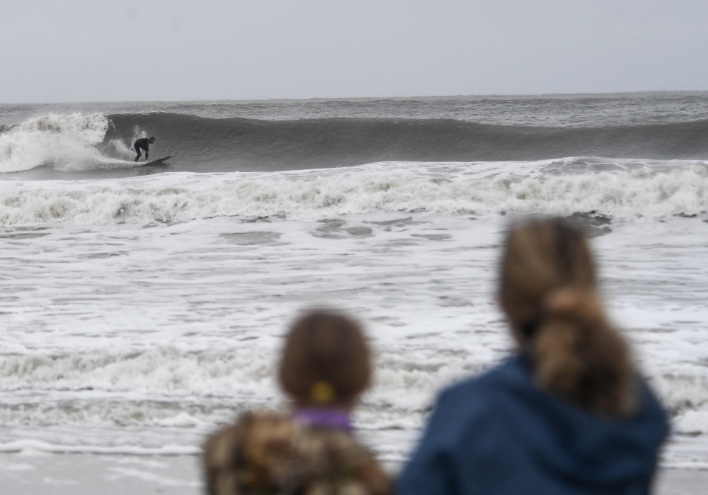People watch a surfer ride the choppy waves in Ocean City, New Jersey, on September 26, 2026.  (Photo by Matthew HATCHER / AFP)