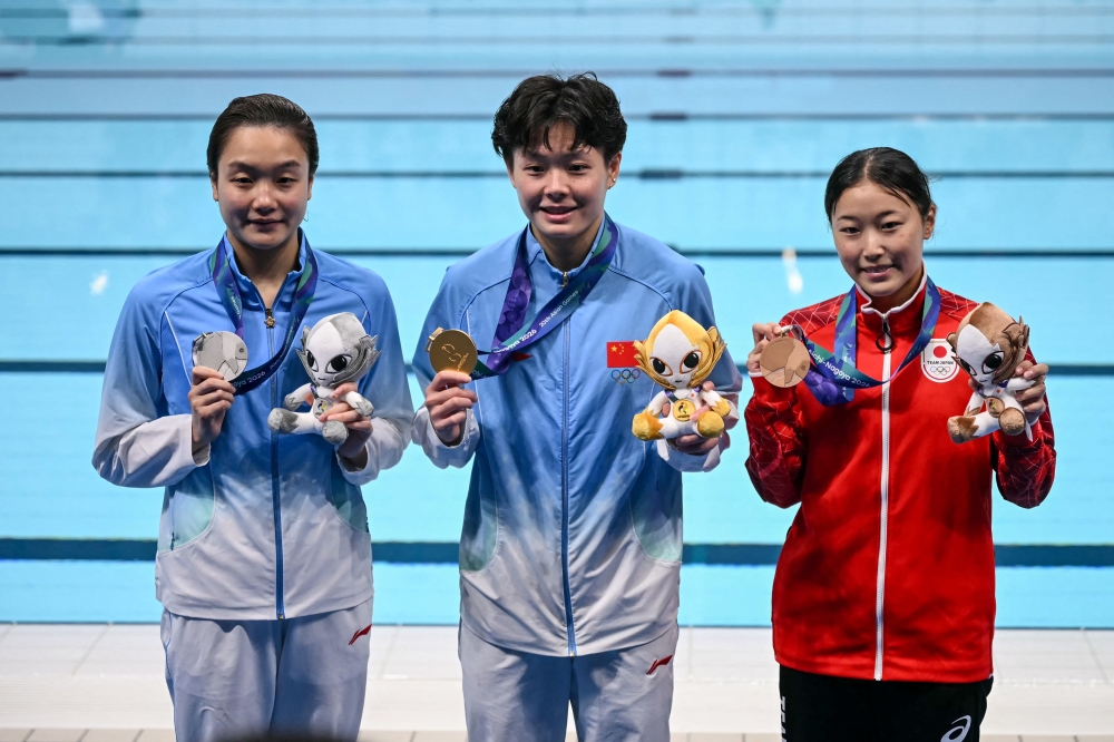 Silver medallist China's Chen Jia (L), gold medallist China's Chen Yiwen (C) and bronze medallist Japan's Sayaka Mikami (R) pose following the victory ceremony of the women's 3m springboard final diving event. (Photo by Andrew Caballero-Reynolds / AFP)