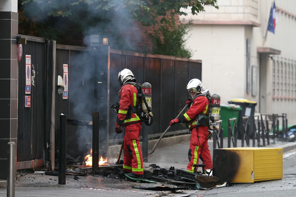 Firefighters extinguish a fire at the entrance of the Leonard de Vinci secondary school following a blockading action by protesting students, in Paris on October 2, 2026. (Photo by Thomas SAMSON / AFP)