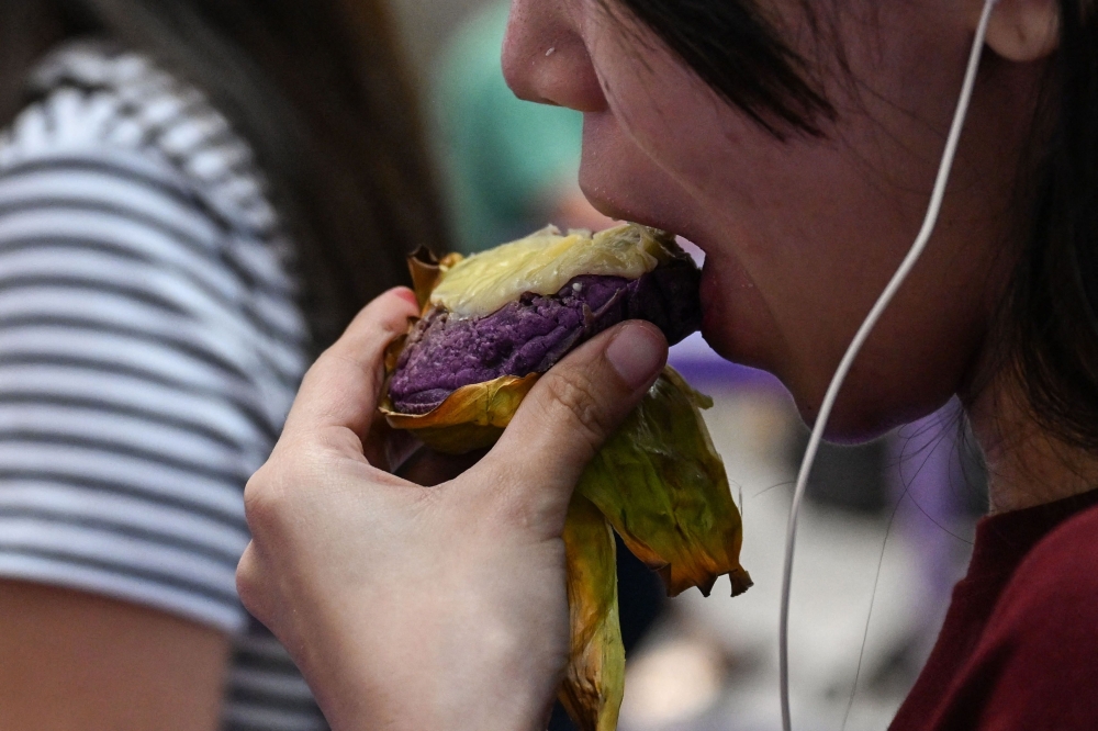 This photo taken on September 23, 2026 shows a customer eating an ube bibingka (baked rice cake) at a mall in Quezon City, Metro Manila. (Photo by Jam Sta Rosa / AFP) 