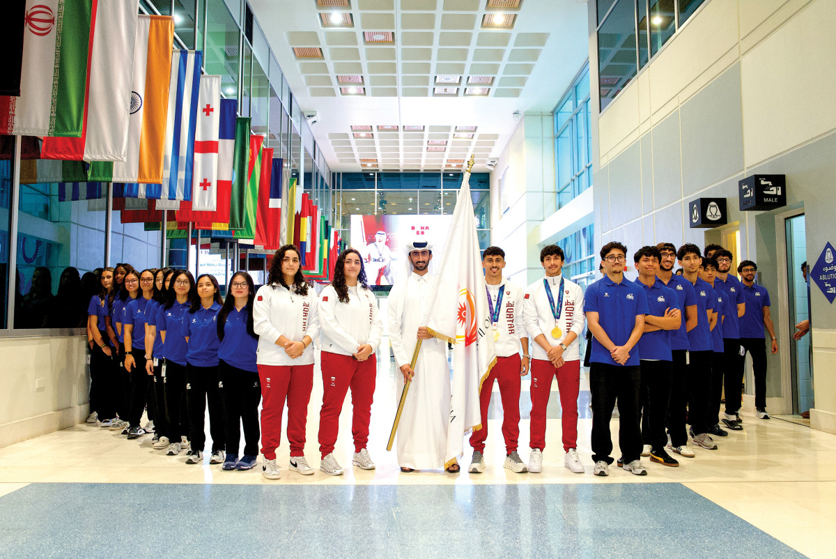 Equestrian rider Jassim Al Kuwari holds the Asian Games Flag alongside Team Qatar’s padel and women’s basketball players and students at the University of Doha for Science and Technology.