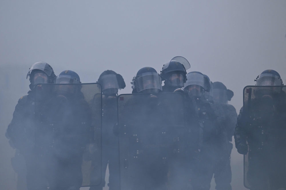 French gendarmes stand amidst tear gas during a demonstration in favor of purchasing power, the protection of public services, and fiscal and social justice, in Nantes, western France on October 24, 2026 (Photo by Guillaume Saligot / AFP)