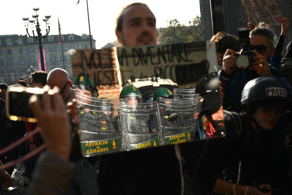 A protester holds a mirror to Guardia di Finanza officers during a demonstration part of a nationwide day of strikes and protests as school and university students demand more funding for schools and support for housing, in Turin on October 30, 2026. Photo by Marco BERTORELLO / AFP