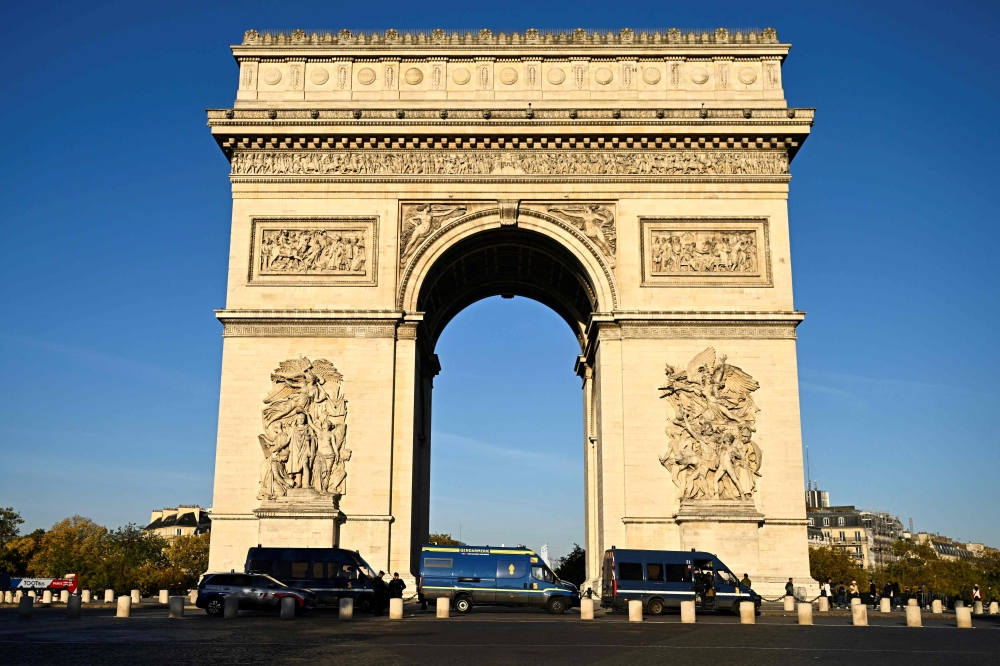 Gendarmes' vehicles surround the Arc de Triomphe in Paris on October 31, 2026. (Photo by Julien De Rosa / AFP)